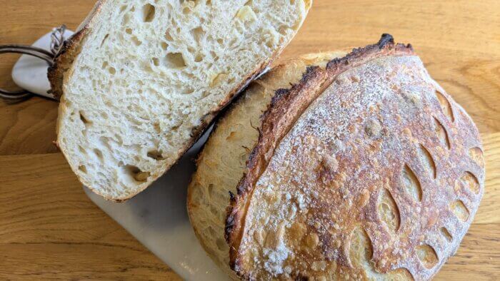 2 loaves of roasted garlic sourdough bread with one that has been cut resting on the other