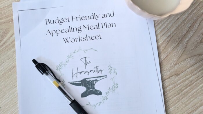 free downloadable meal planning worksheet with a pen on top and an unlit corner in the top right