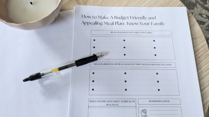 free downloadable meal planning worksheet with a pen on top and an unlit candle in the corner