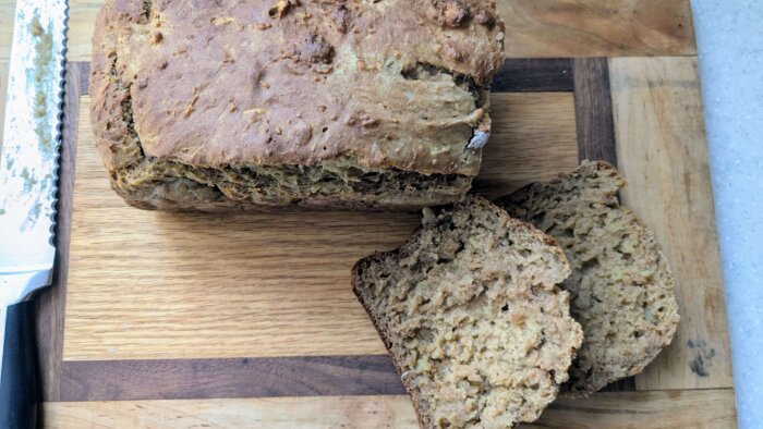 baked sweet potato bread on a cutting board with two slices next to it 