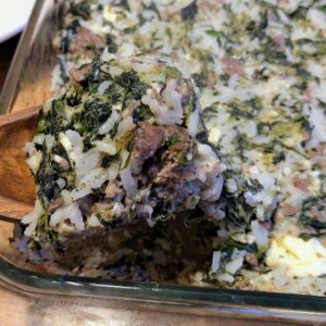 baked spinach and feta casserole being scooped out of a baking pan with a wooden spoon