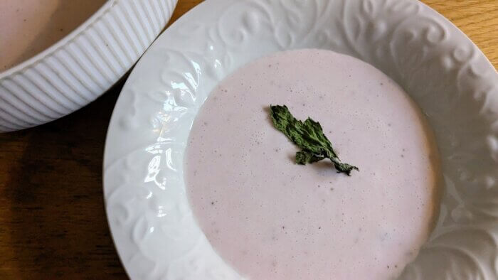 a bowl of strawberry bisque topped with dried mint,