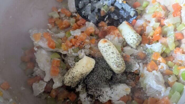 butter and herbs in a Dutch oven with celery, carrots, onions, and chicken 