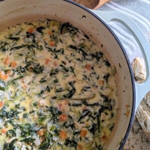 Chicken Florentine Soup in a Dutch oven next to sliced sourdough bread