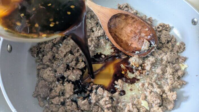 pouring a sauce over ground beef 