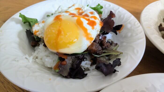 Korean Ground beef over rice and salad greens with a fried egg and hot sauce 
