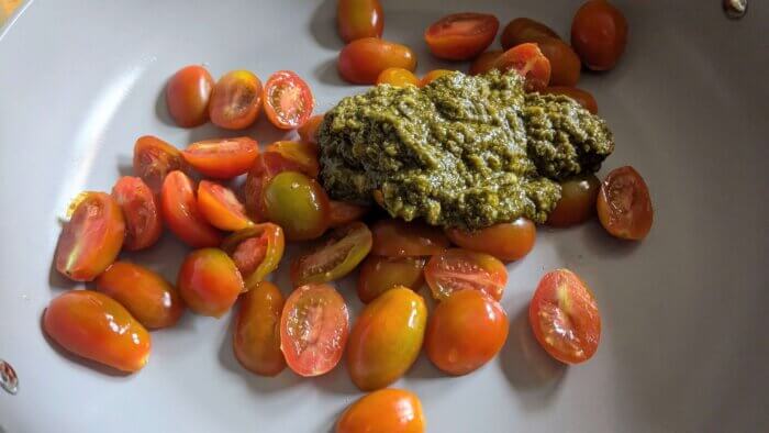 halved cherry tomatoes and pesto in a skillet 