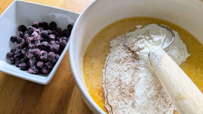 a bowl of frozen blueberries next to a bowl with sourdough discard Blueberry muffin batter 