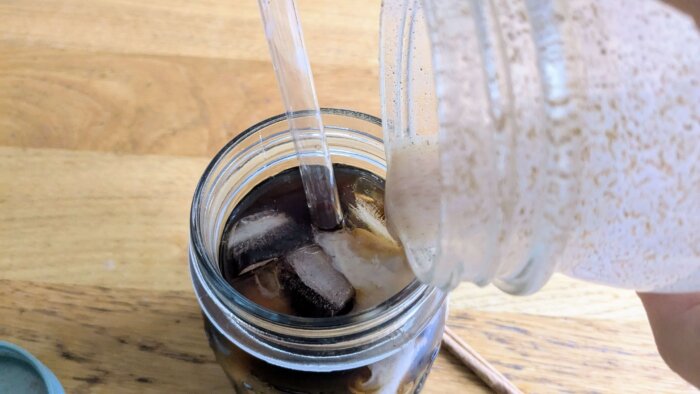 Honey Cinnamon Latte milk being poured into a mason jar of coffee