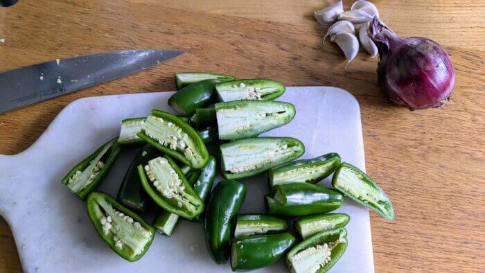 jalapenos sliced in half on a marble cutting board