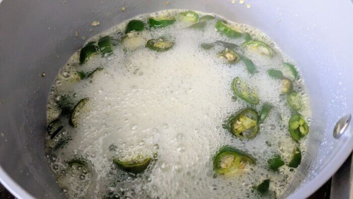 jalapenos in boiling liquid candying liquid in a sauce pan