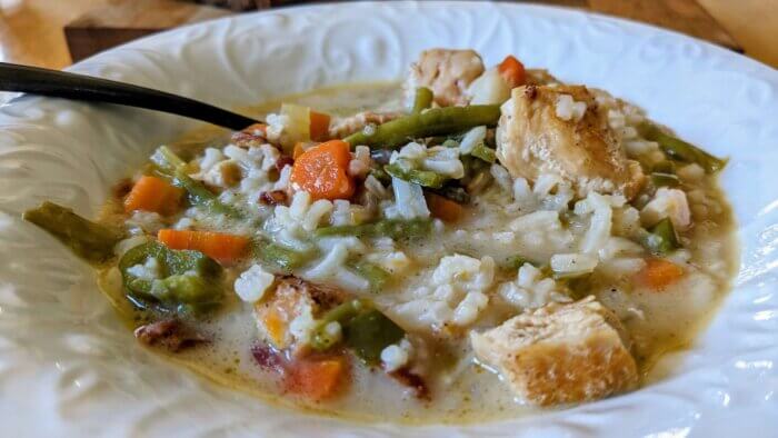 creamy chicken soup and vegetables in a white bowl