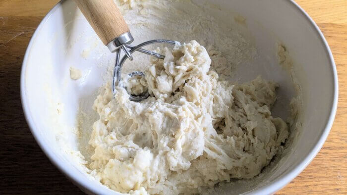 sourdough pizza dough ingredients being incorporated with a dough whisk