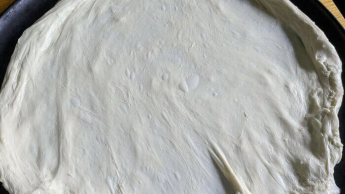 Sourdough Pizza Dough spread out on a pizza pan