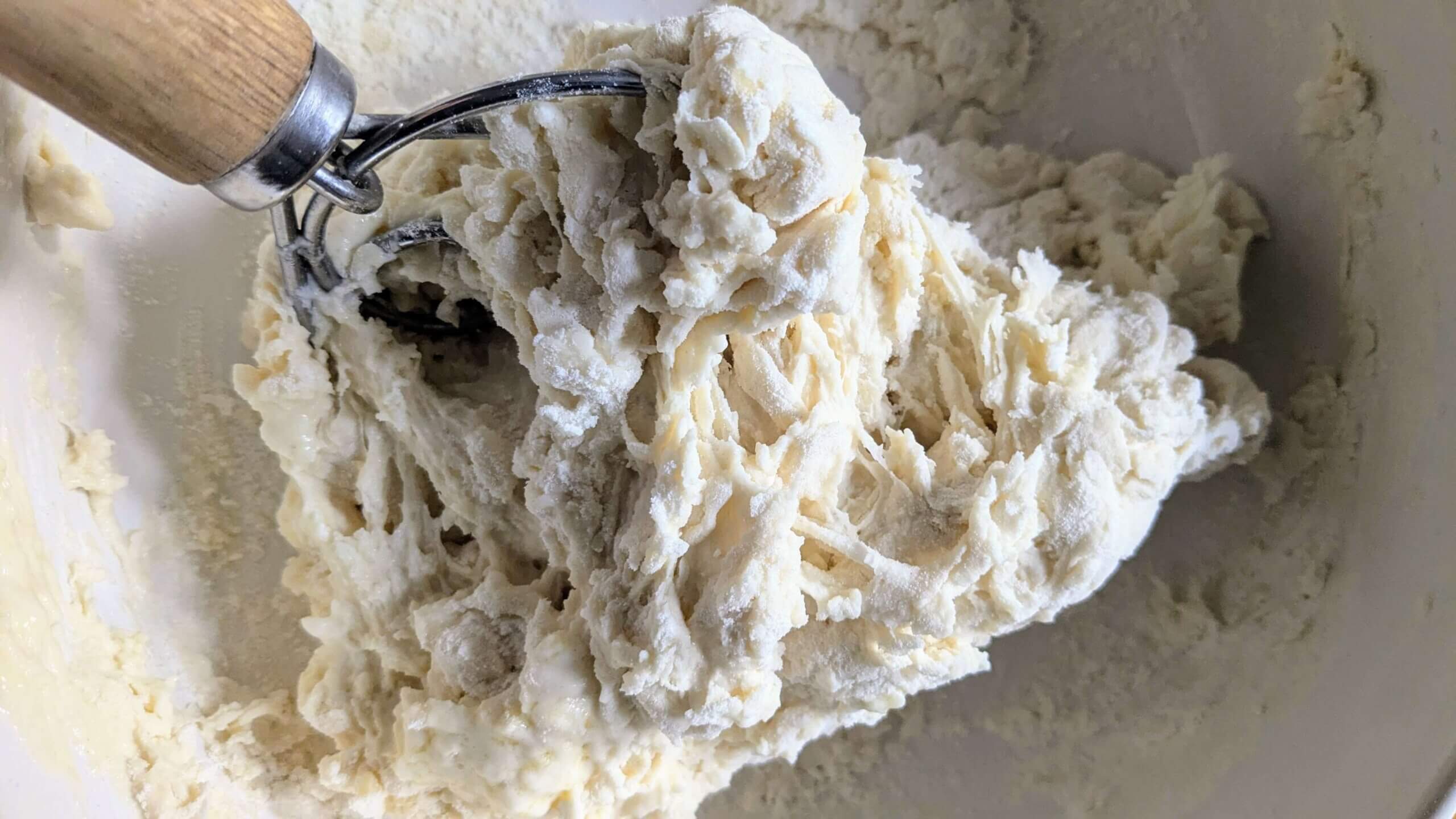 sourdough pizza dough ingredients being incorporated with a dough whisk