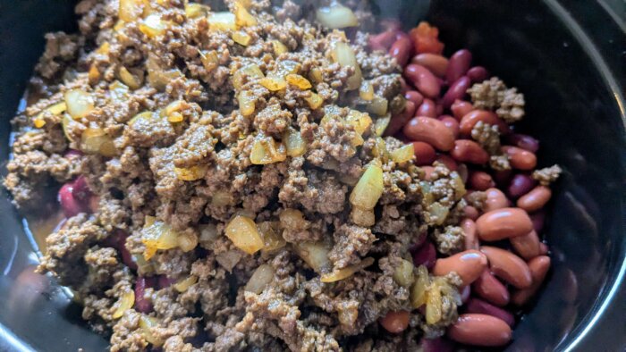 cooked ground beef added to a crock pot with beans and tomatoes. 