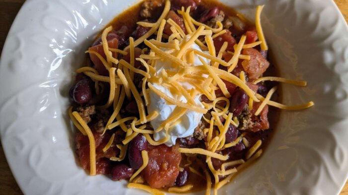 a bowl of crockpot chili topped with sour cream, and cheese