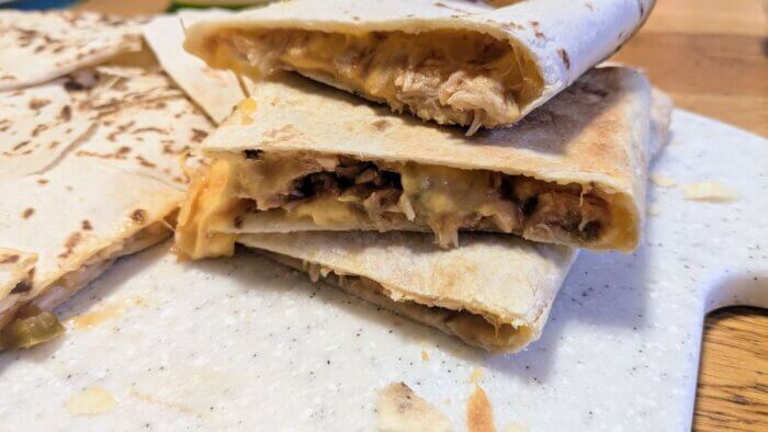 three chicken sheet pan quesadilla stacked on each other on a white cutting board